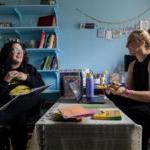 Education professor Taryn Robertson, 左, and Madeline Dearie '25 sit in Robertson's office, talking to each other over her desk.